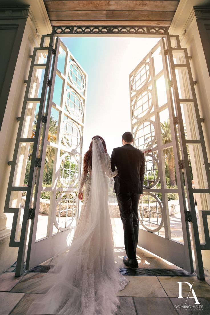 a bride and groom are walking out of an open door