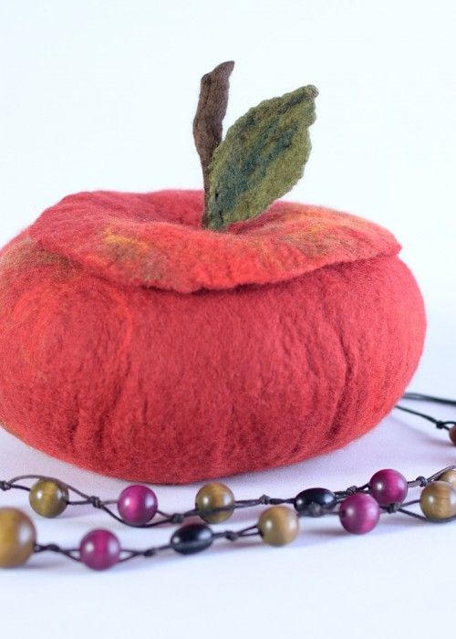 a red apple with a green leaf on it next to a beaded necklace and beads