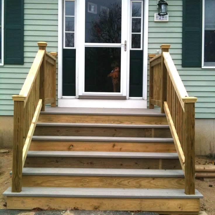 a dog is standing at the door of a house with steps leading up to it