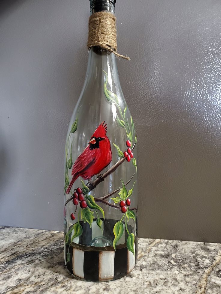 a glass bottle with a cardinal painted on it