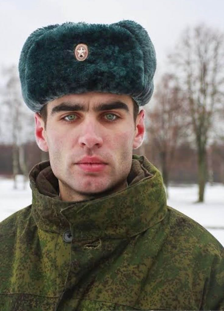 a man wearing a green hat and jacket in the snow