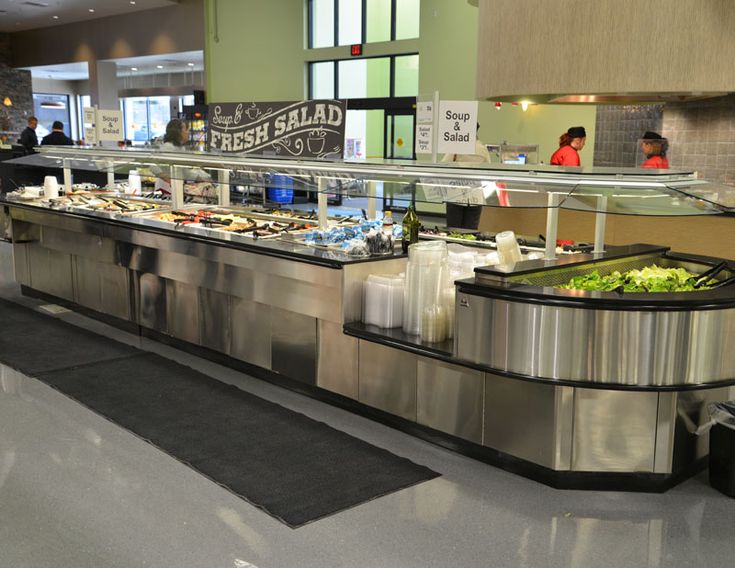 an empty buffet area in a restaurant with people standing around and eating food on the counter