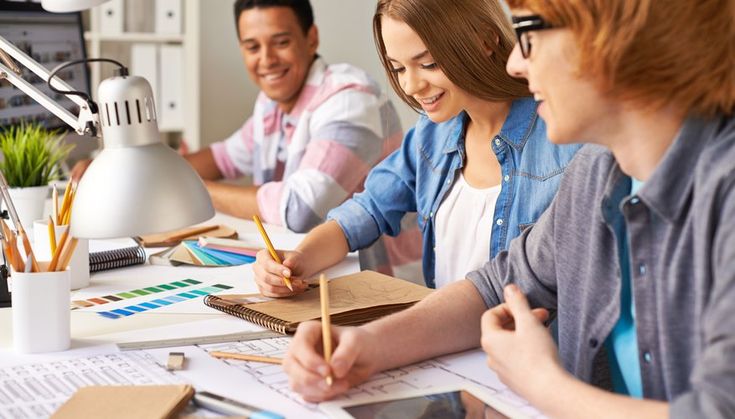 three people sitting at a table with papers and pencils