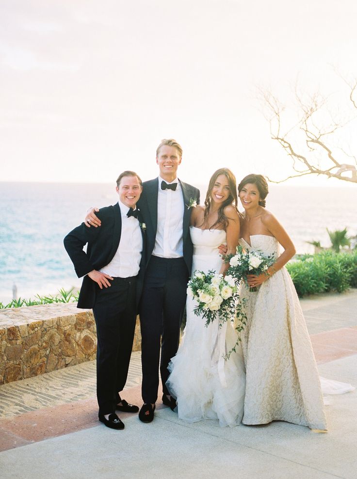 a bride and groom posing for a photo with the ocean in the background