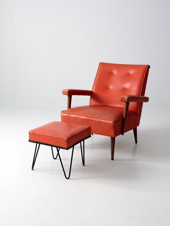 an orange chair and footstool sitting next to each other on a white background