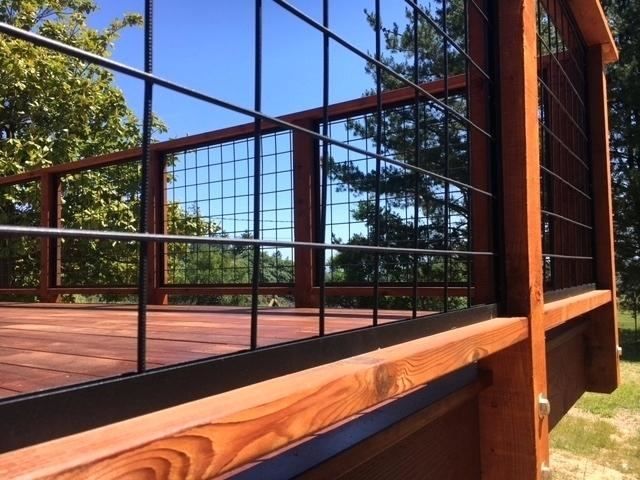 a wooden deck with metal railings and wood slats on the sides, along with trees in the background