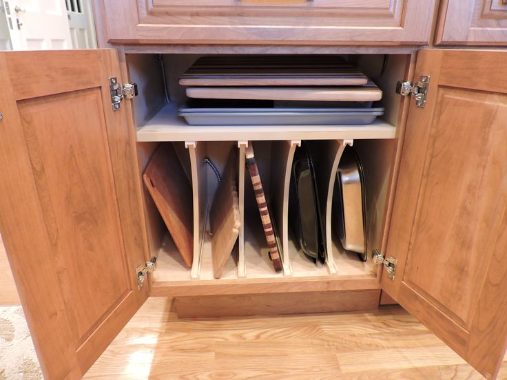 the kitchen cabinets are open to show dishes and utensils in their drawer compartments