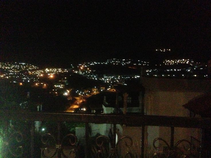 the city lights are lit up in the night sky from an apartment balcony at night