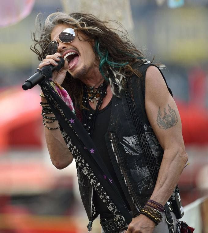 a man with long hair singing into a microphone