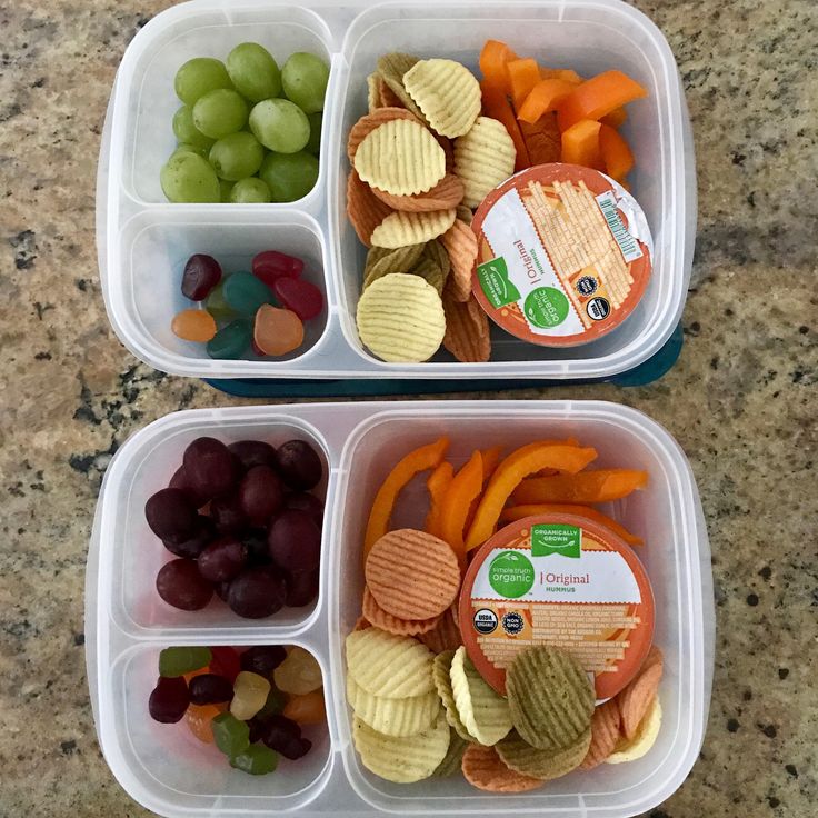 two plastic containers filled with fruit and crackers