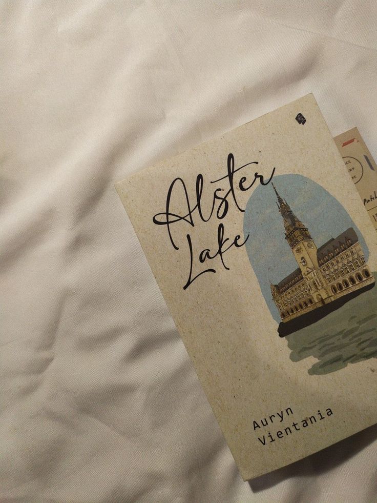 an old book is laying on a bed with white sheets and the title also lake written in black ink