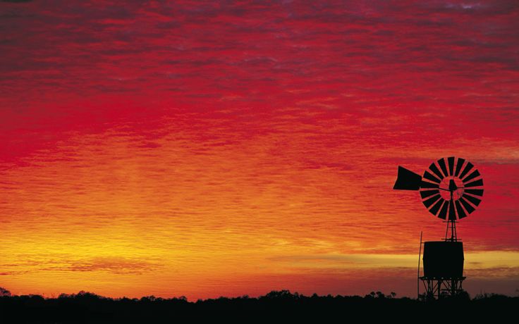 an orange and red sunset with a windmill in the foreground