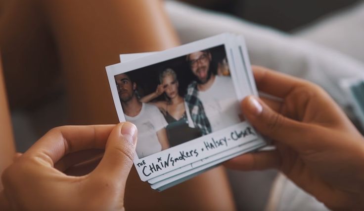 a person holding up a polaroid with an image of two women on it in front of them