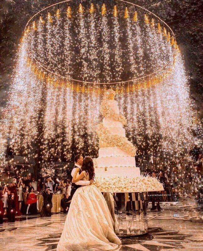 a bride and groom are kissing in front of a wedding cake surrounded by sparkles