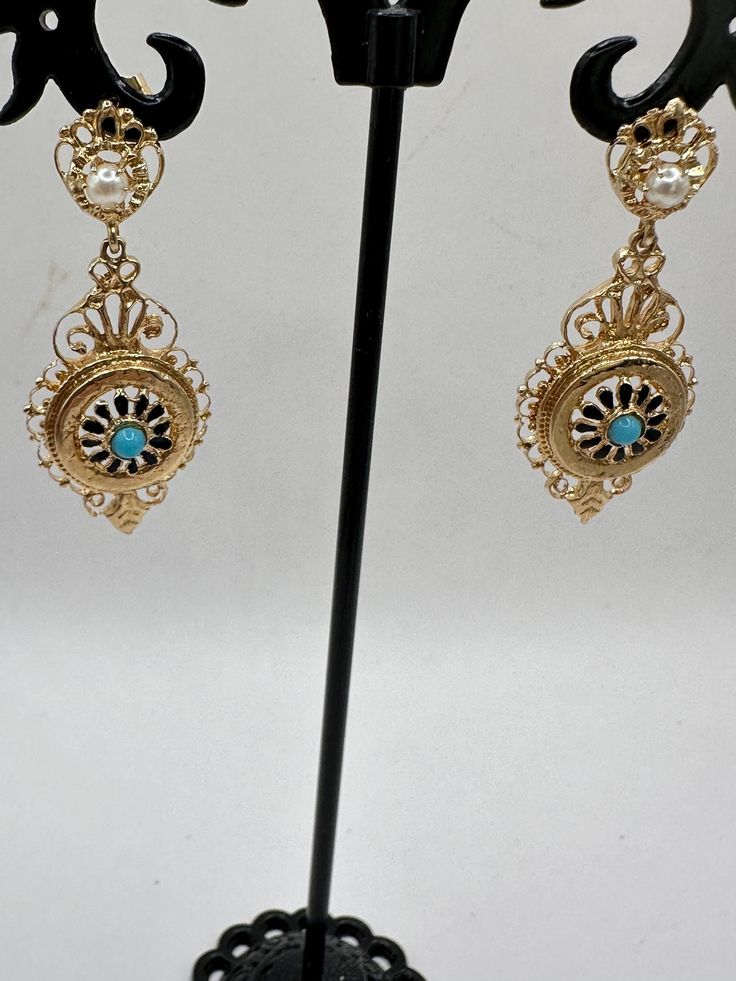 A unique opportunity for a wonderful pair of vintage 14K yellow gold dangle earrings. These unique earrings are hallmarked 14K on the bottom dangle and are guaranteed to be such. These gorgeous earrings have 2 dangles. The top dangle looks like a circle, which houses a 3.3mm pearl and what looks to be a crown. The bottom dangle features an elaborate design with a center blue stone, perhaps a tourquoise? The intricacy of the design is impressive. These are post earrings with butterfly closures. These beauties are 2 3/4" long and just under 3/4" at their widest. They are an impressive 6.31 grams. These are fabulous pair of earrings and perfect for a special occasion or for that person who just wants some thing very different! Antique 14k Gold Hallmarked Earrings, Vintage Yellow Gold Evening Earrings, Vintage Yellow Gold Earrings For Evening, Victorian Gold Plug Earrings, Antique Yellow Gold Drop Earrings, Vintage 14k Gold Filigree Earrings, Vintage 14k Stamped Earrings For Formal Occasions, Antique Filigree Chandelier Earrings For Formal Occasions, Victorian Style Hallmarked Earrings For Formal Occasions