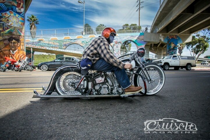 a man riding on the back of a motorcycle down a street next to a bridge