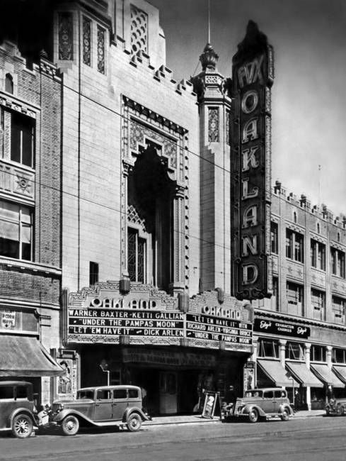 an old movie theater with cars parked in front