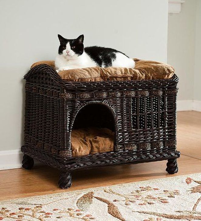 a black and white cat laying on top of a wicker dog bed in a living room