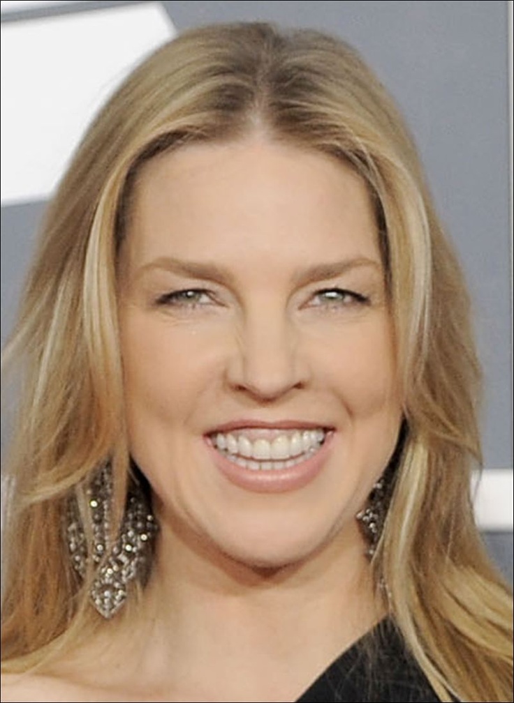 a woman with long blonde hair smiling at the camera and wearing earrings on her head