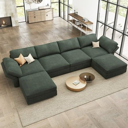 a living room with a large sectional couch and coffee table in the middle, surrounded by windows