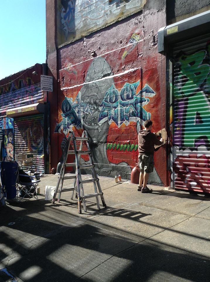 a man is painting graffiti on the side of a building in an alleyway with scaffolding and ladders