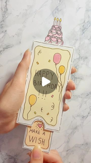 someone holding up a card with a birthday cake on it