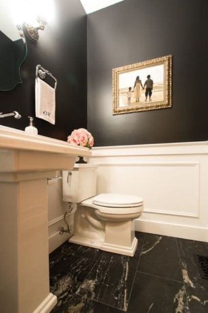 a white toilet sitting next to a sink in a bathroom under a painting on the wall