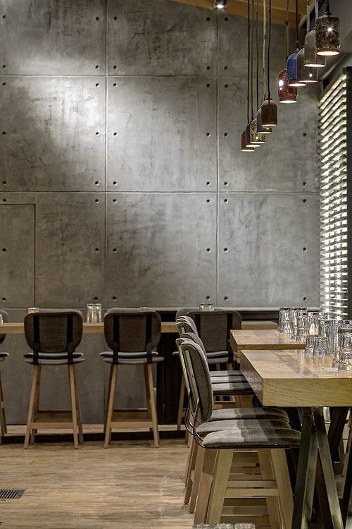 an empty restaurant with wooden tables and chairs in front of a wall that has metal panels on it