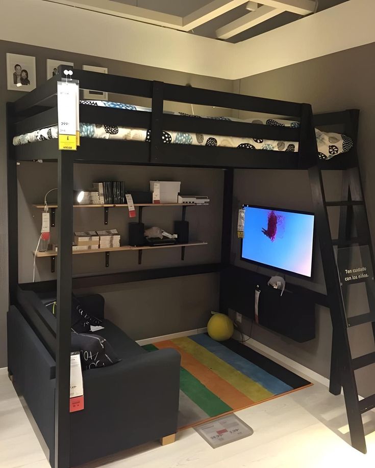 a loft bed with a desk underneath it and a tv on the bottom shelf in front of it