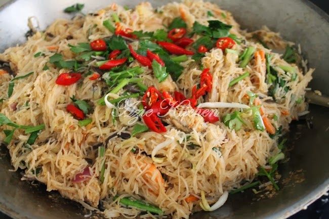 a pan filled with noodles and vegetables on top of a stove next to a frying pan