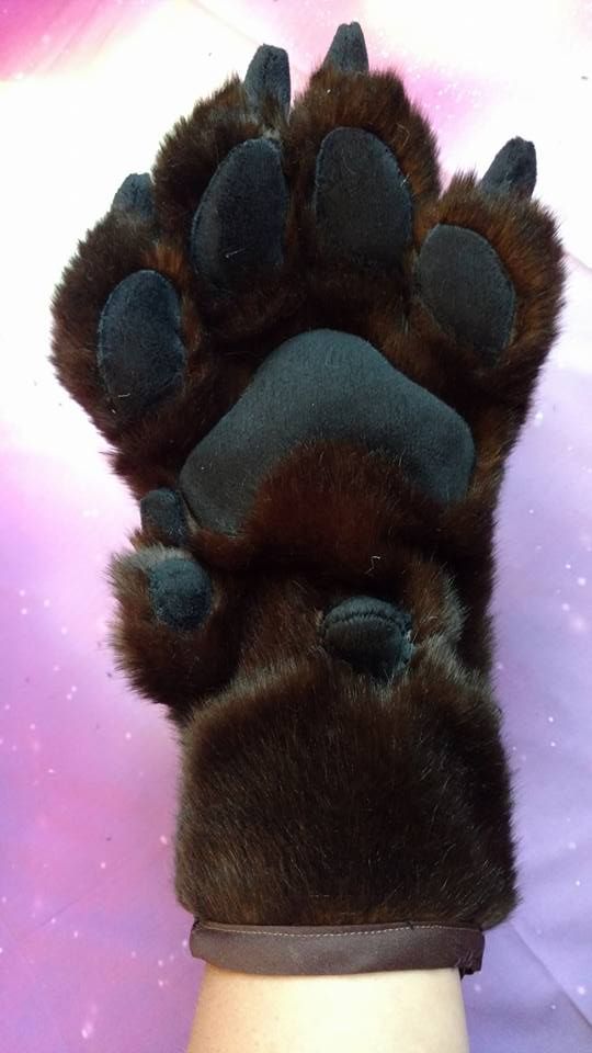 a person's hand wearing a brown and black furry animal paw glove on top of their arm