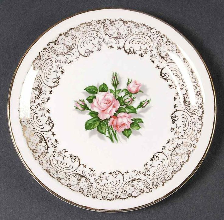 a white and black plate with pink flowers painted on it's side, against a gray background