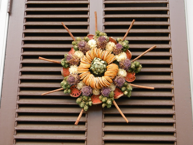 a wreath made out of fruits and vegetables on the side of a window sill