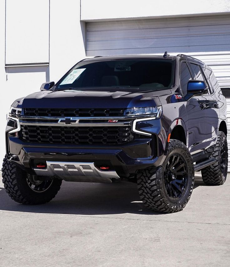 a large black truck parked in front of a garage