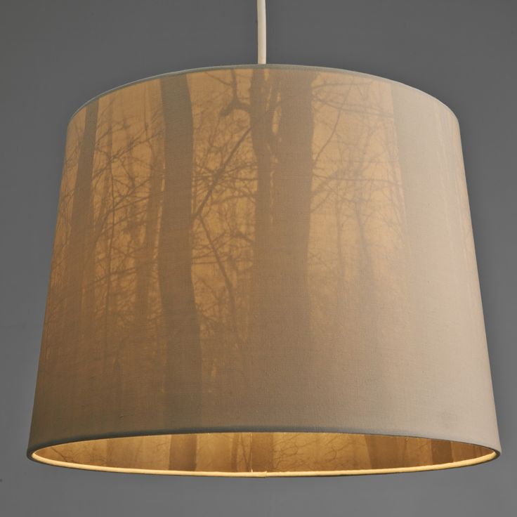 a lamp hanging from a ceiling with trees in the background and light shining on it