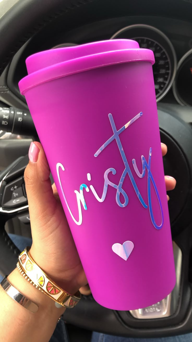 a person holding up a purple cup with the word christ on it in their hand