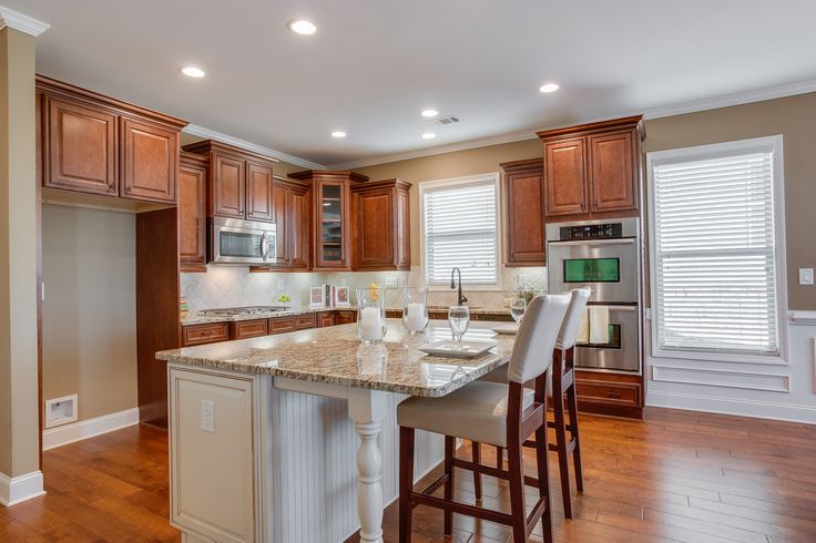 a large kitchen with wooden floors and white counter tops, along with an island in the middle