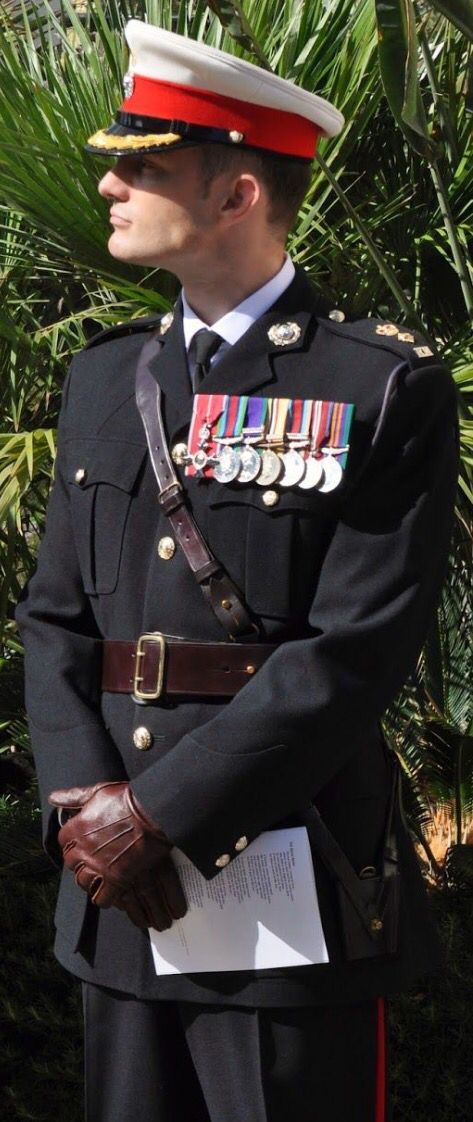 a man in uniform standing next to a palm tree