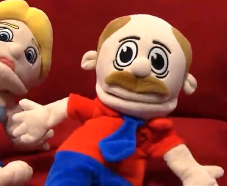 two stuffed toys sitting next to each other on a red couch with one holding the other's hand