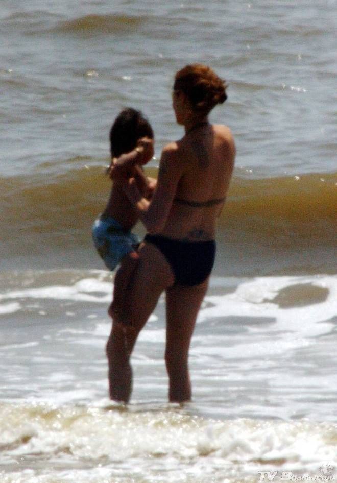 two women in bikinis are standing in the water at the beach and one is holding her head