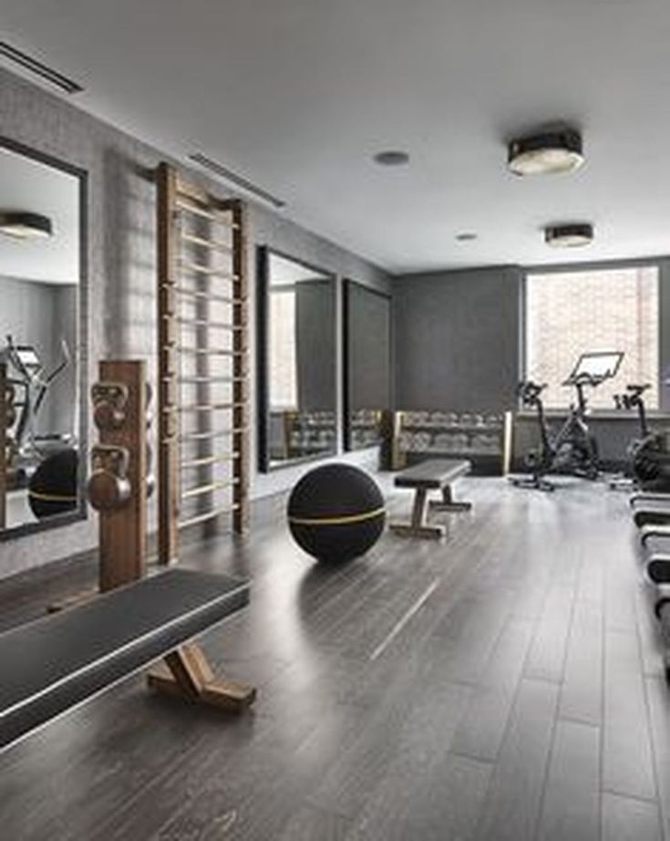 a gym with exercise equipment and mirrors in the wall, along with treadmills