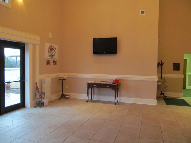 a living room with tile flooring and a flat screen tv mounted on the wall