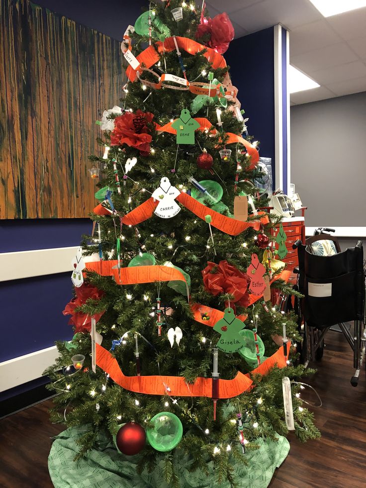 a decorated christmas tree in an office cubicle with orange and green ribbon on it