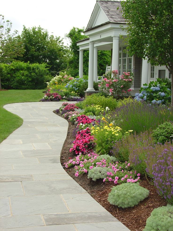 an image of a garden with flowers in the front yard and landscaping on the other side