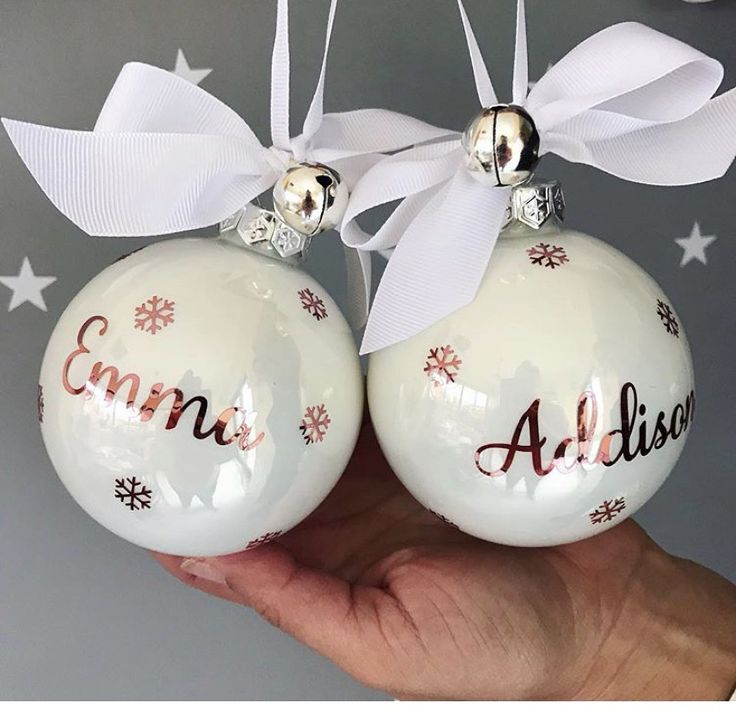 two white christmas baubles with red lettering and snowflakes hanging from them