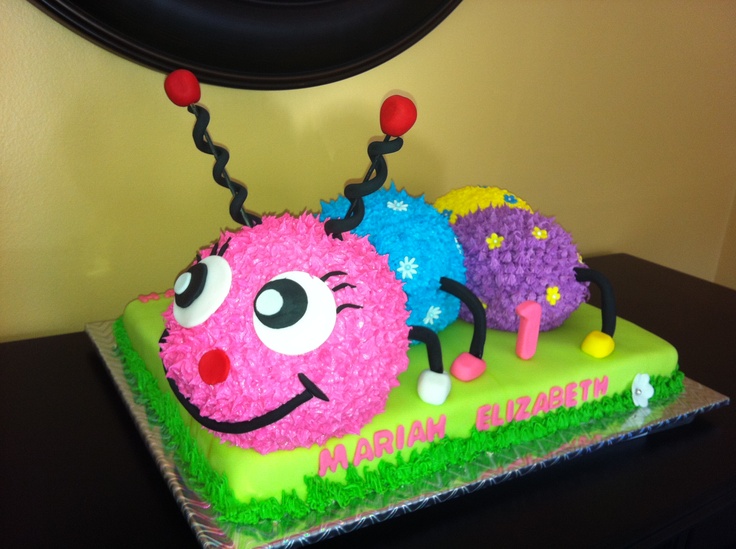 a birthday cake decorated with three colorful caterpillars