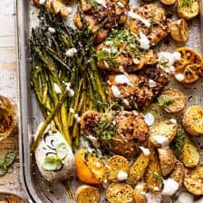 a pan filled with chicken, potatoes and asparagus on top of a table