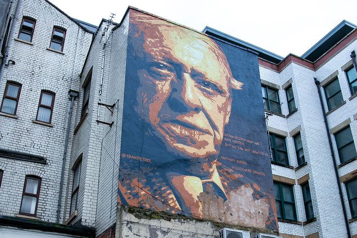 a large painting of a man on the side of a building in front of some buildings