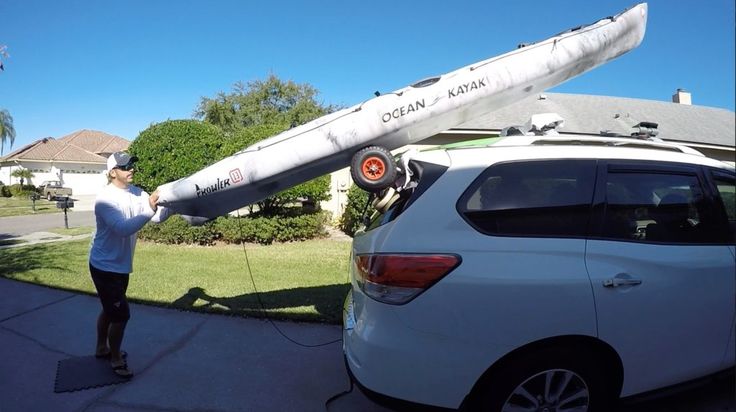 a man standing next to a white car with an airplane on it's roof