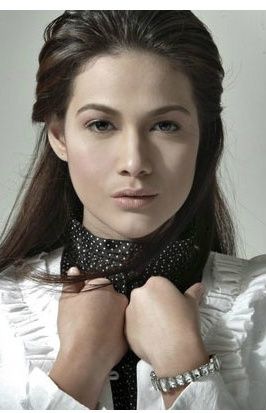 a woman wearing a white shirt and black tie with her hands on her chest looking at the camera